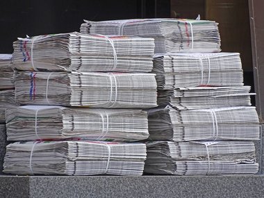Einige Stapel mit Tageszeitung vor einem Kiosk.
