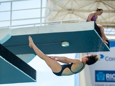 Eine Sportlerin im Badeanzug bei einem Salto in der Luft.