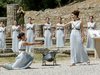 Frauen, die das olympische Feuer in Athen auf einer Wiese präsentieren.