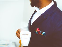 Ein Mann mit Anzug und einer Kaffeetasse.