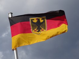 Perspektive-Deutschland Stimmung: Eine Deutschlandfahne mit dem schwarzen Adler flattert vor grauem Himmel.