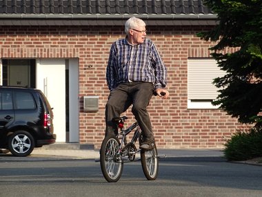 Ein rüstiger Rentner fährt rückwärts auf einem Mountainbike.