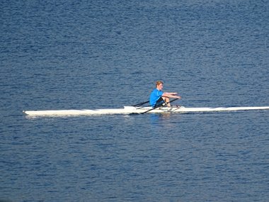 Ein Ruderer auf einem See mit einem türkisem Tshirt.