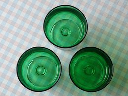 Drei grüne Schalen aus Glas stehen auf einer karierten Tischoberfläche.