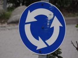 Ein blaues Schild mit Pfeilen für einen Kreisverkehr.