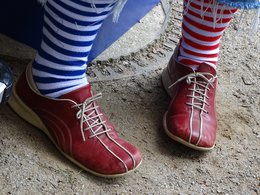 Rote Schuhe mit blau und rot geringelten Socken.
