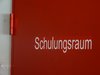 Weiterbildungsratgeber: Eine rote Tür mit weißer Schrift für einen Raum mit der Beschriftung: Schulungsraum.