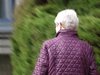 Eine Seniorin mit lila Jacke geht spazieren.