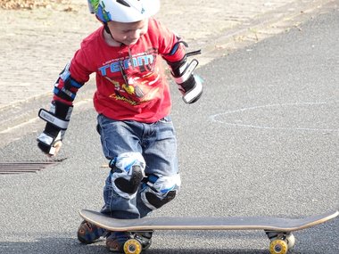 Ein Junge mit Schützern und seinem Skateboard.