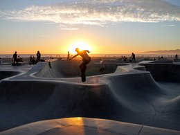 Ein Junge mit seinem Skateboard beim Sprung in den Sonnenuntergang.