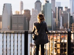 Eine Frau steht auf einem Zaun und schaut auf eine Skyline.