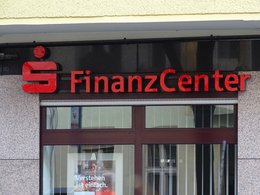Eine Eingangstür mit dem Zeichen der Sparkasse und den Worten: Finanz Center mit roten, plastischen Buchstaben.