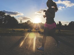 Eine Frau joggt im Sonnenuntergang durch einen Park.