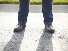 Schuhe und Unterschenkel eines stehenden Mannes.