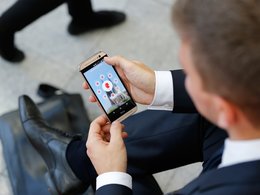 Jobbörsen-Kompass 2018: Das Foto zeigt einen Wirtschaftswissenschaftler im Anzug der die Jobbörse für WiWis von Staufenbiel.de auf dem Smarthone aufruft.