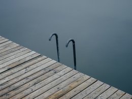Ein Holzsteg mit einer Leiter zum Hochklettern aus dem Wasser.