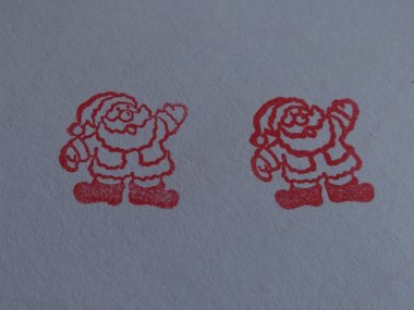 Zwei roter Stempel von einem Weihnachtsmann auf einem weißen Blatt Papier.