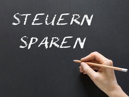 Kreise-Schriftzug "STEUERN SPAREN" auf einer schwarzen Tafel.