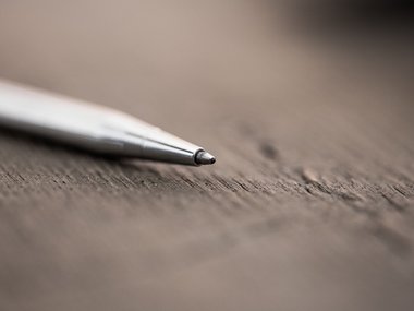 Ein Kugelschreiber liegt auf einem Holzuntergrund.