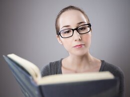 Das Bild zeigt eine Studentin mit Brille, die ein Buch liest.