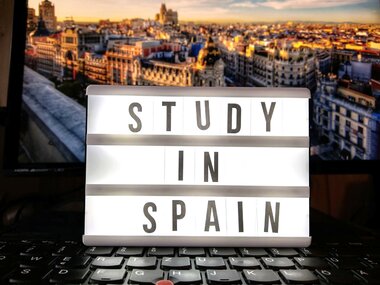 Ein Lichtkasten zeigt die Worte Studieren in Spanien in Englisch. Im Hintergrund ist die Statt Madrid zu sehen.