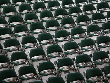 Ein Bild voller leerer, grüner, hochgeklappter Stühle mit einer Armlehne.