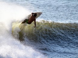 Ein Surfer, der mit seinem Brett auf einer Welle reitet.