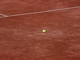 Der Ausschnitt eines Tennisfeldes mit weißen Linien.