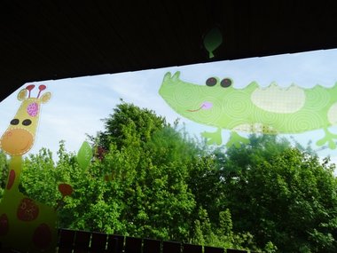 Eine Giraffe und ein Krokodil als Aufkleber an einer Fensterscheibe vor grünem Hintergrund.