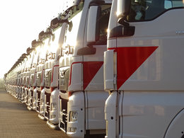 Das Bild zeigt eine lange Reihe von LKW und symbolisiert die Transportbranche.