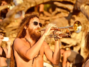 Ein Mann mit langen Rastahaaren spielt auf einer Trompete.