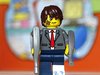 Ein Lego-Männchen im Anzug mit einem Gipsbein, Plaster und Verletzungen im Gesicht und Gehstützen..