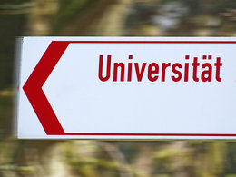 Der rote Schriftzug "Universität" auf einem weißen Schild weist den Weg zur Uni.
