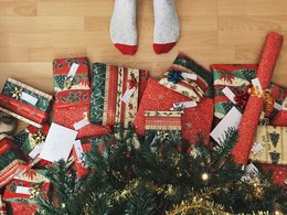 Päckchen in rot-grünem Papier liegen unter einem Weihnachtsbaum.