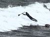 Ein Surfer mit Brett und Paddel fällt gerade in eine Welle.