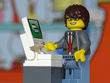 Wirtschaftsinformatiker - Das Bild zeigt ein Lego-Männchen im Anzug vor einem Computer.