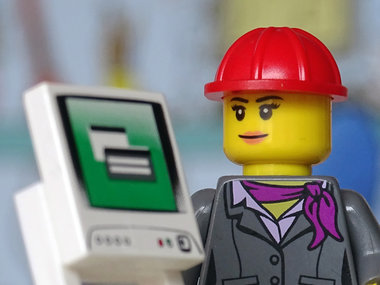 Stepstone Gehaltsreport 2014: Wirtschaftsingenieurin - Das Bild zeigt eine Lego-Frau im Kostüm mit Helm vor einem Computer.