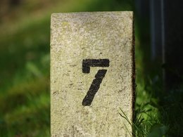 Die Zahl 7 auf einem Grenzstein mit grünem Hintergrund.