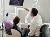 Zahnzusatzversicherung: Ein Zahnarzt erklärt einer Patientin am Röntgenbild die Behandlung.